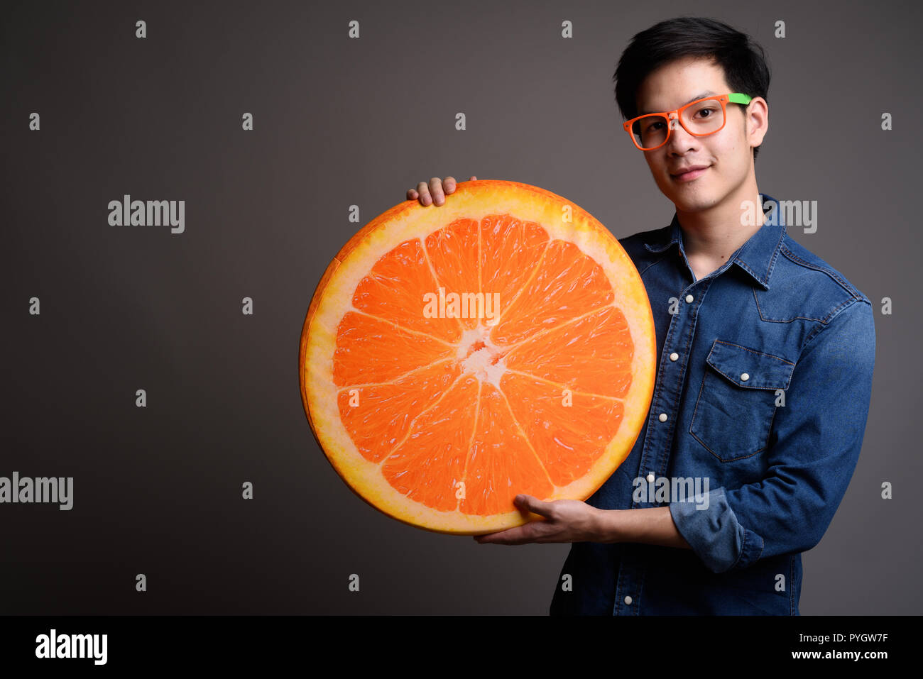 Bel giovane uomo asiatico holding arancione cuscino di frutta Foto Stock