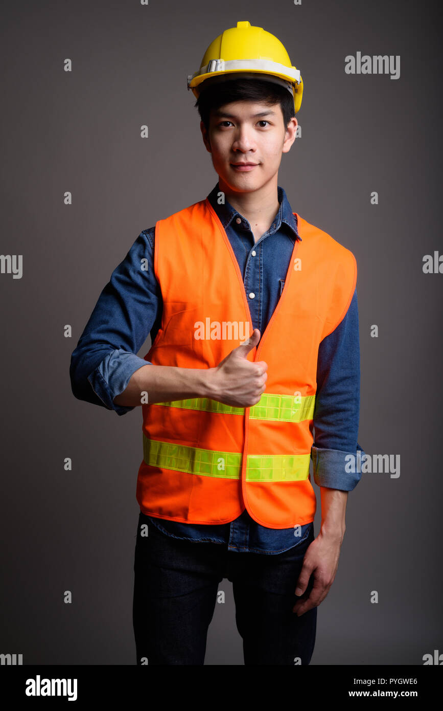 Fiducioso uomo asiatico lavoratore edile dando pollice in alto Foto Stock