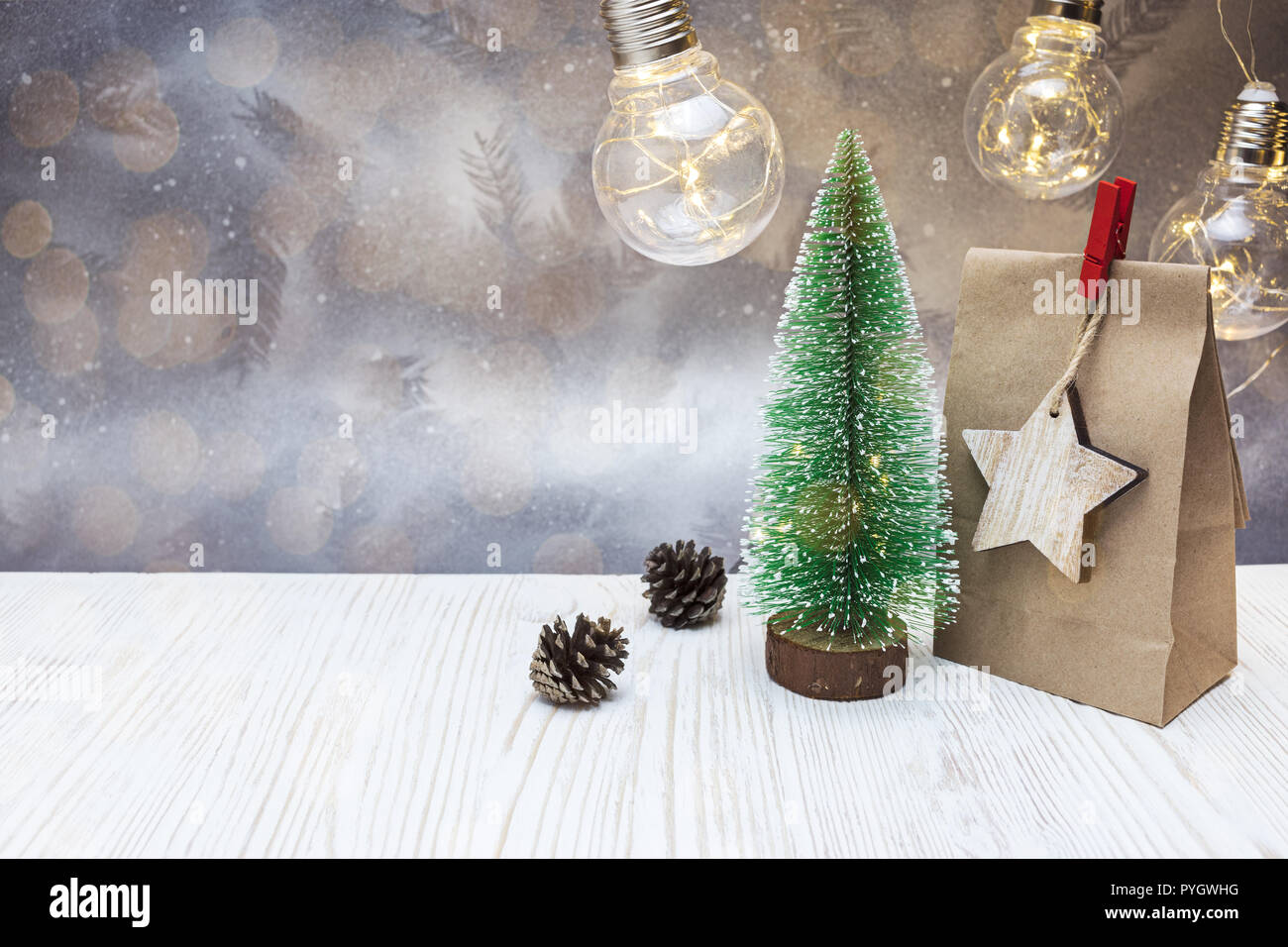 Decorazione di natale con piccoli falso albero verde, carta regalo e sacchetto vecchio ghirlande di lampada Foto Stock
