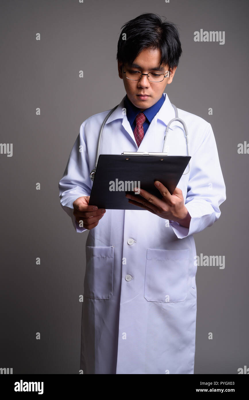 Ritratto di giovane uomo asiatico medico diagnosi di lettura dagli appunti Foto Stock