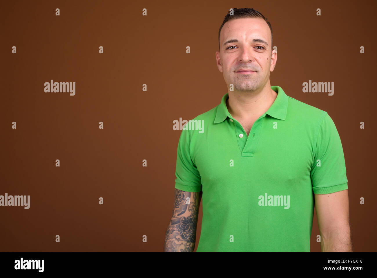 Uomo che indossa camicia verde contro lo sfondo marrone Foto Stock