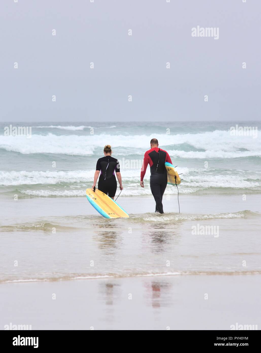 Un uomo e una donna a piedi in mare con pannelli del corpo,Perranporth Beach,Cornwall,l'Inghilterra,UK Foto Stock