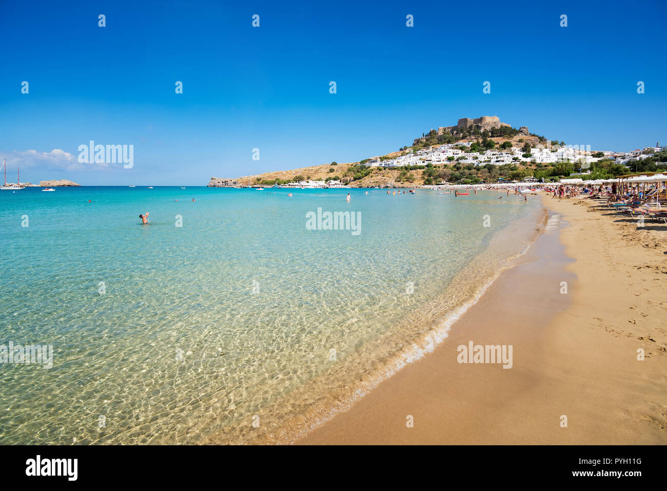 Vista della spiaggia di sabbia della baia di Lindos Acropoli di sfondo (Rhodes, Grecia) Foto Stock