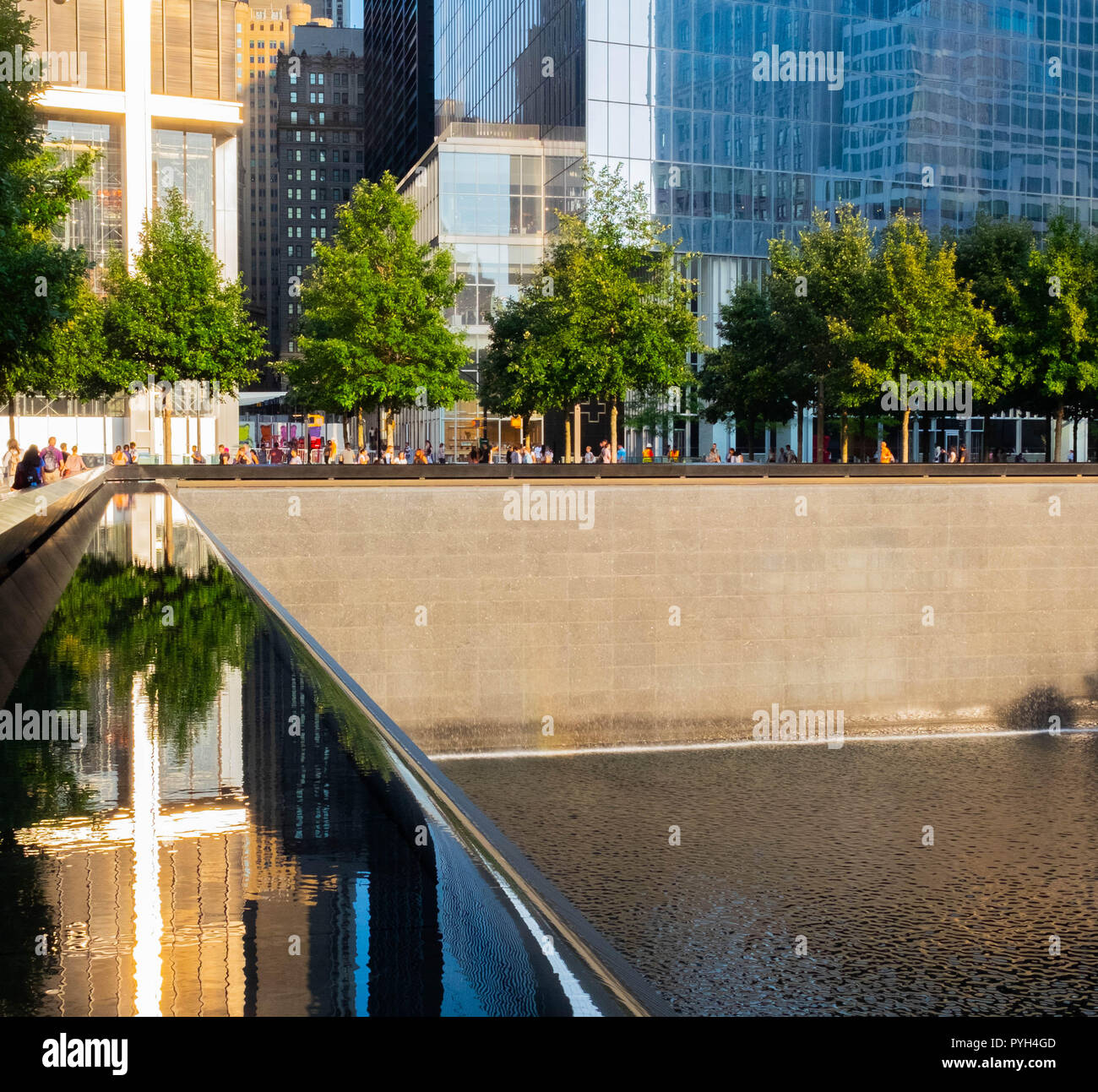 Il sole che splende su un edificio sembra evidenziare una croce alle fontane del World Trade Center Memorial dell'11 settembre a Lower Manhattan, New York City Foto Stock