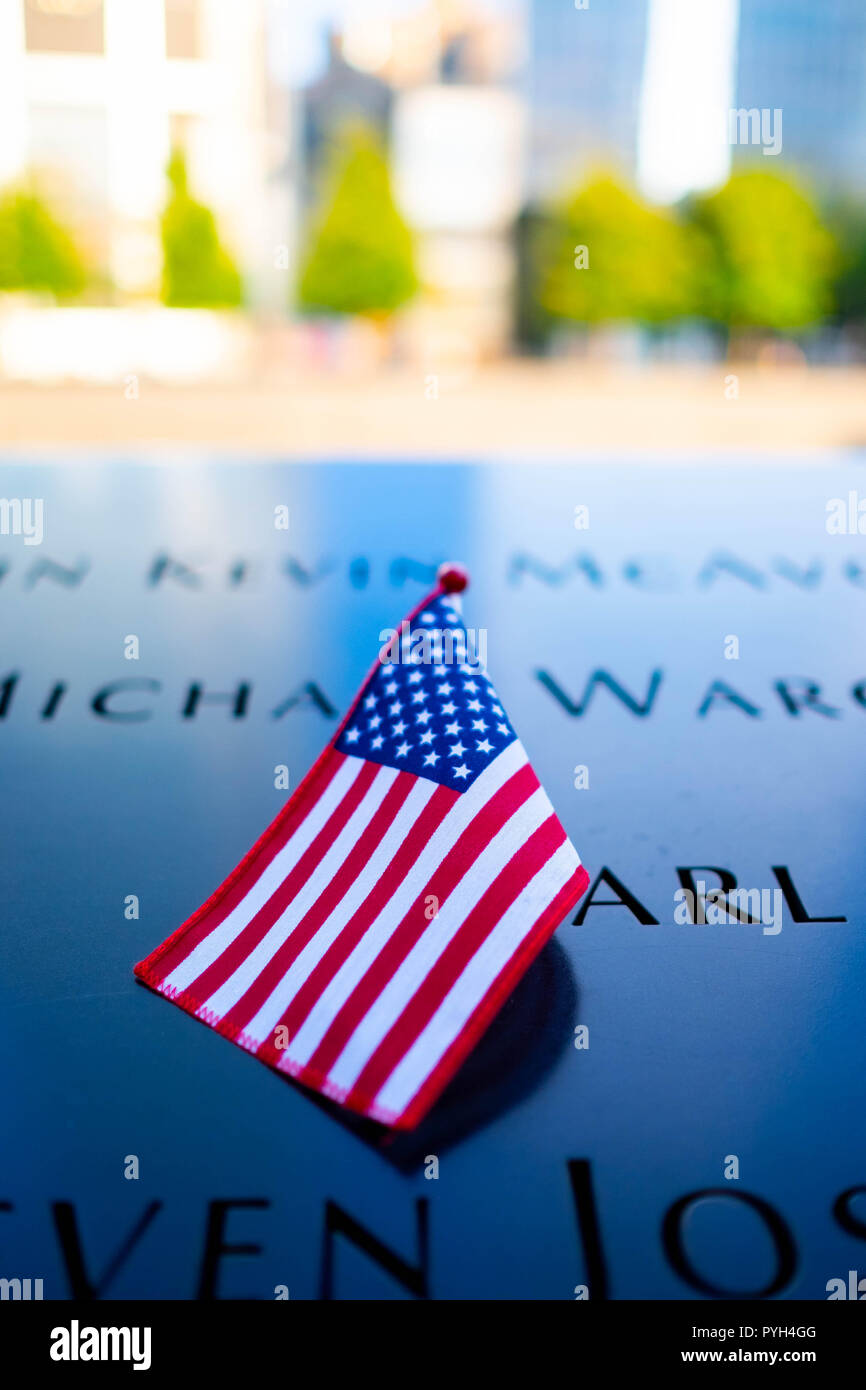 I nomi di alcune delle vittime contrassegnati da una bandiera americana sulla 9/11 World Trade Center Memorial fontane in Lower Manhattan, New York City Foto Stock