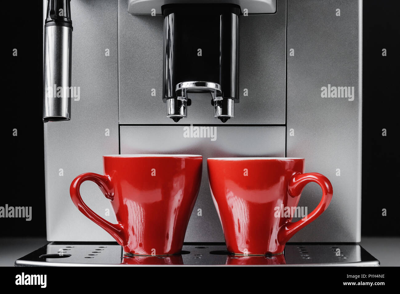Moderno e macchina per il caffè e due bicchieri rossi a sfondo nero, close up Foto Stock