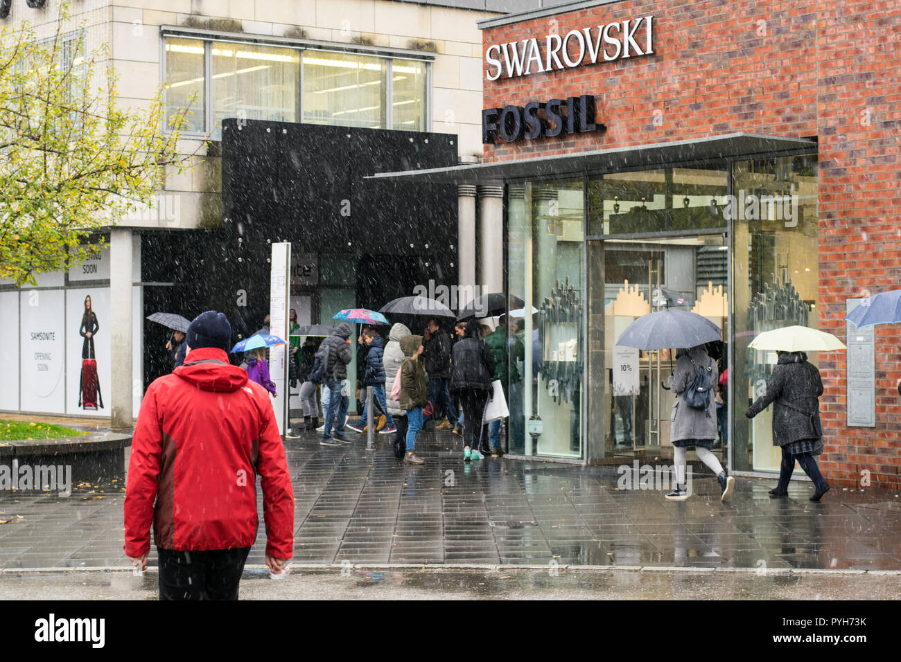 La febbre dello shopping in Outletcity Metzingen, Germania. 28.10.2018, Swarovsky e vendita di fossili. Giorno di pioggia, vista sulla strada, persone e negozi. Foto Stock