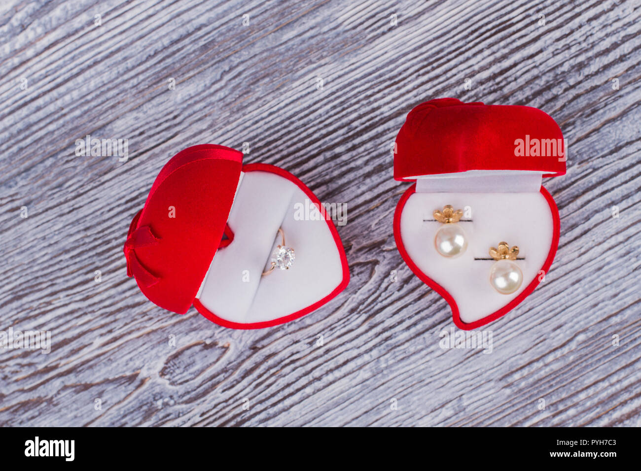 Velluto rosso confezioni regalo con gioielli. Anello di nozze box e box con orecchini perla su sfondo di legno. Regalo romantico concetto. Foto Stock
