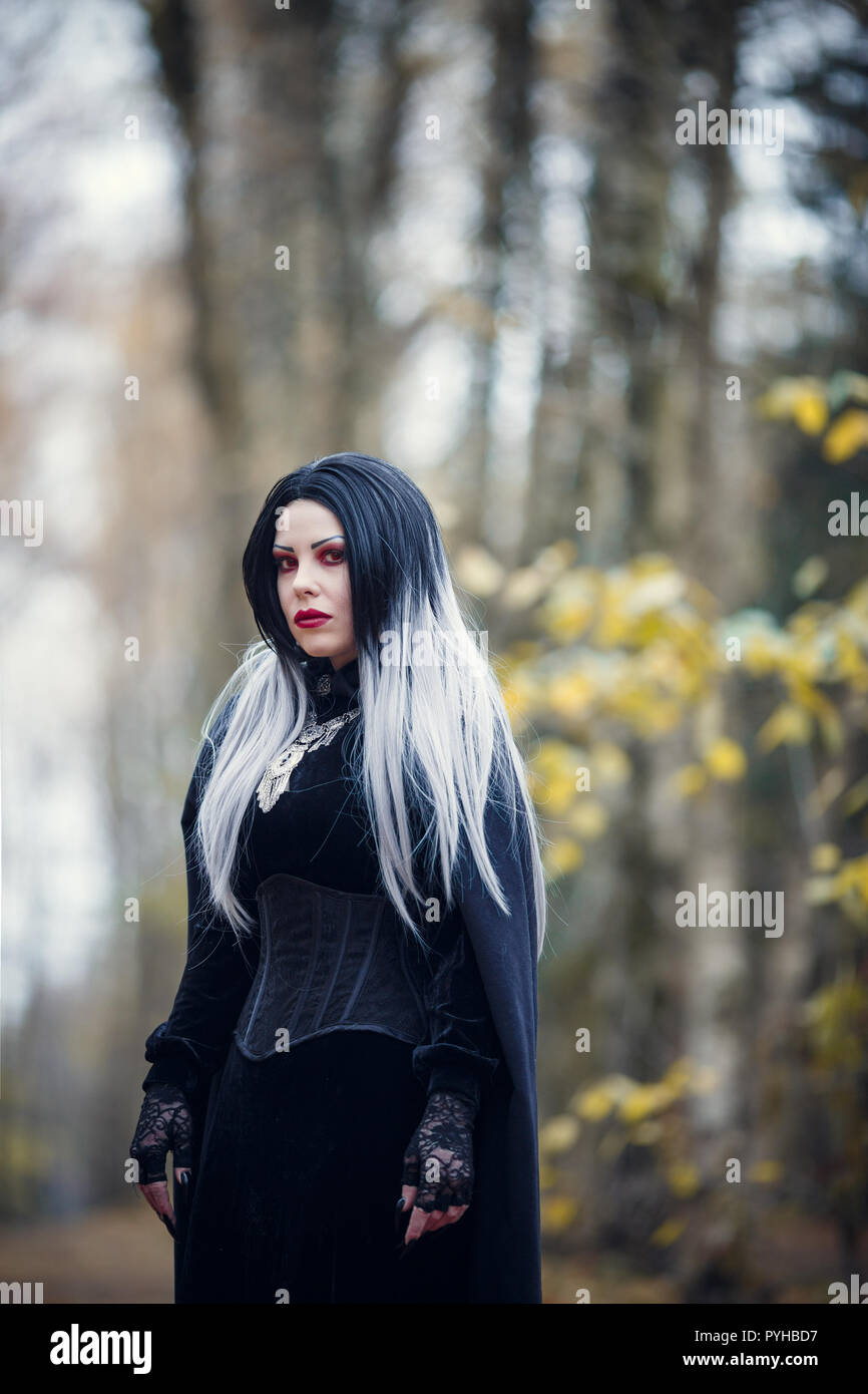 Immagine della donna vampiro nel mantello nero su sfondo sfocato Foto Stock