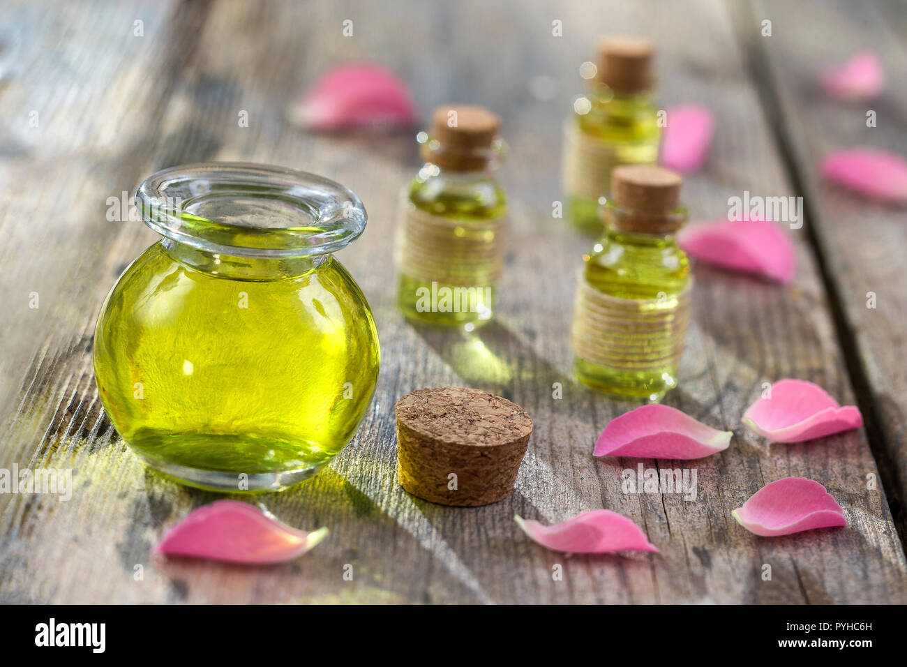 Rose petali di fiori con aromaterapia olio essenziale di bottiglia di vetro isolate su legno, sfondo, copy-spazio Foto Stock