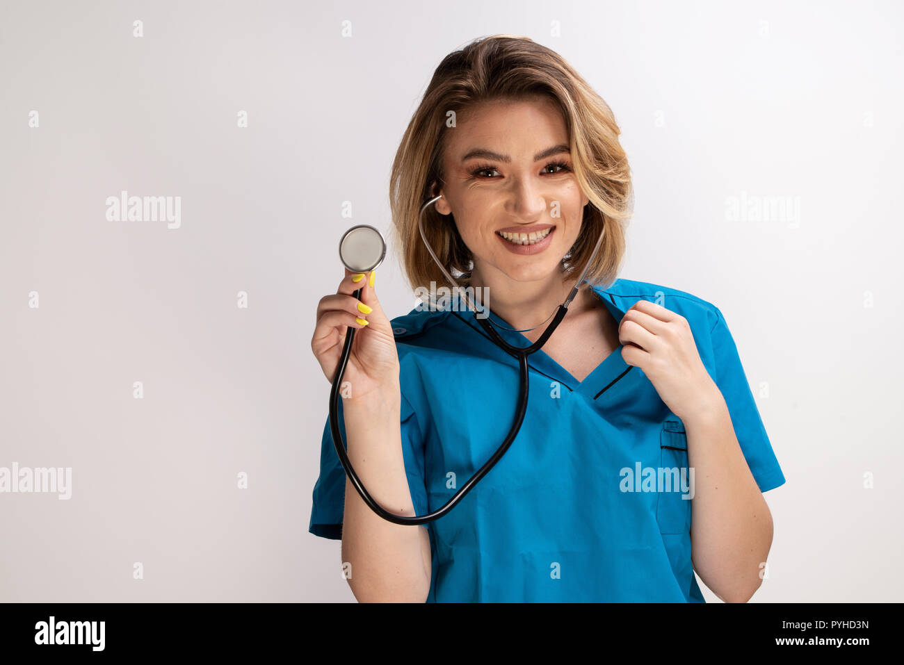 Medico donna visualizzazione di uno stetoscopio per la fotocamera. Colpo isolato su sfondo bianco con spazio di copia Foto Stock