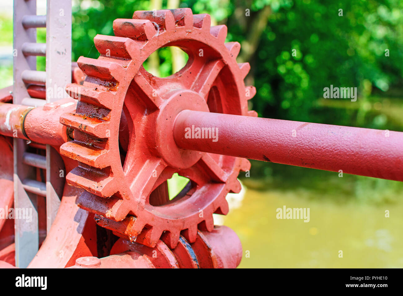 Close-up di un rosso metal gear su la paratoia 7. Meccanismo per aprire la diga. Vecchia ruota dentata sul fiume. Trasferimento all'apertura della diga. Vecchio cogw Foto Stock