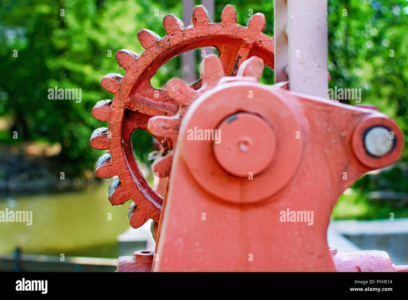 Close-up di un rosso metal gear su la paratoia 7. Meccanismo per aprire la diga. Vecchia ruota dentata sul fiume. Trasferimento all'apertura della diga. Vecchio cogw Foto Stock