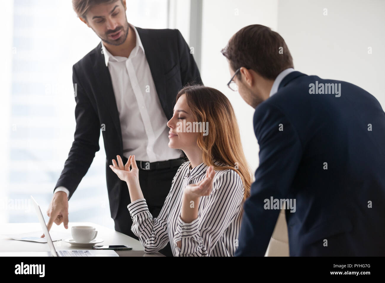 Giovane donna calma meditando nel luogo di lavoro, ignorando i colleghi. Foto Stock