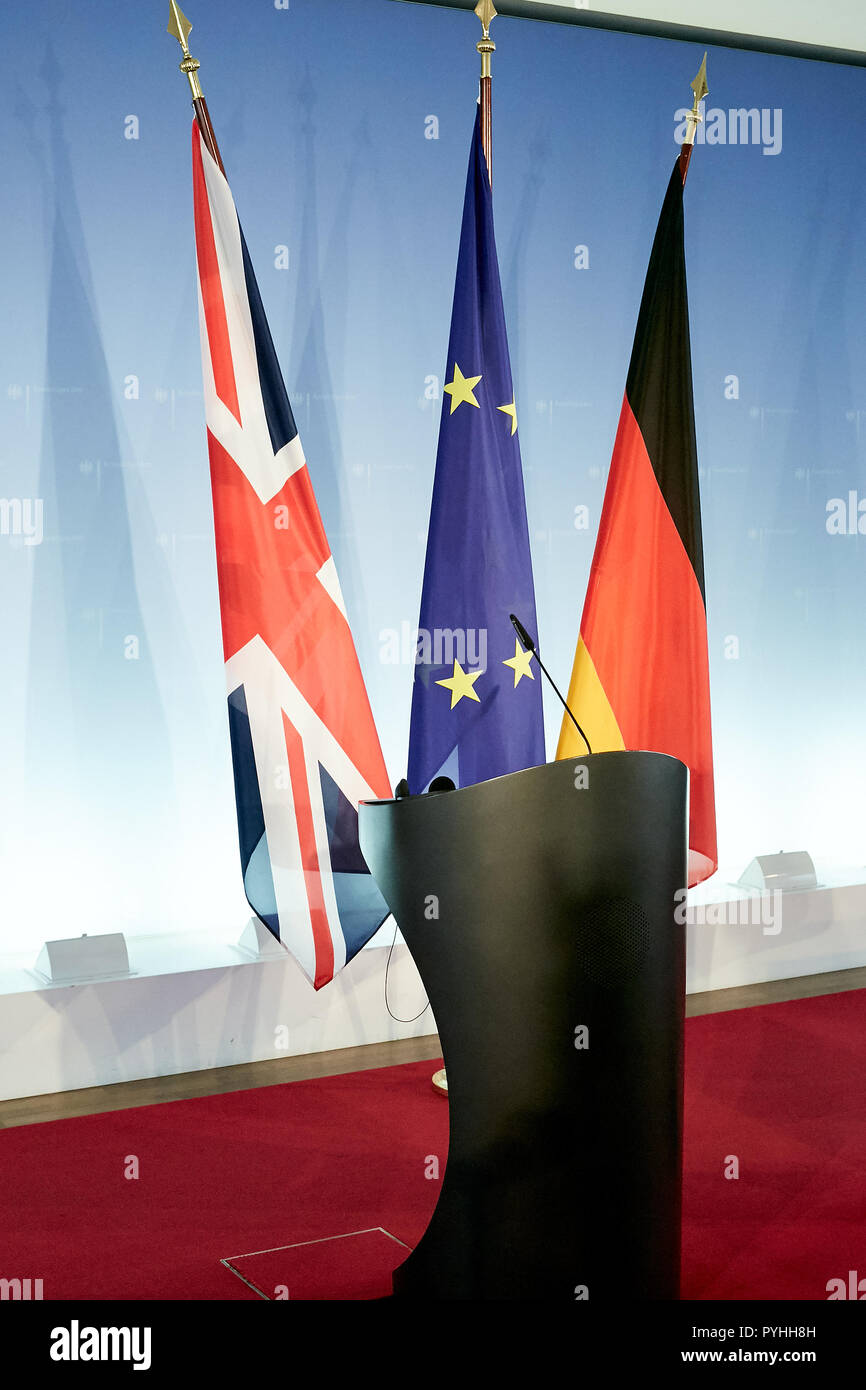 Berlino, Germania - Le bandiere della Gran Bretagna, l'Unione europea e la Germania appendere su standard dietro due scrivanie in piedi di fronte ad una parete del logo in una sala stampa del ministero degli Affari Esteri. Foto Stock