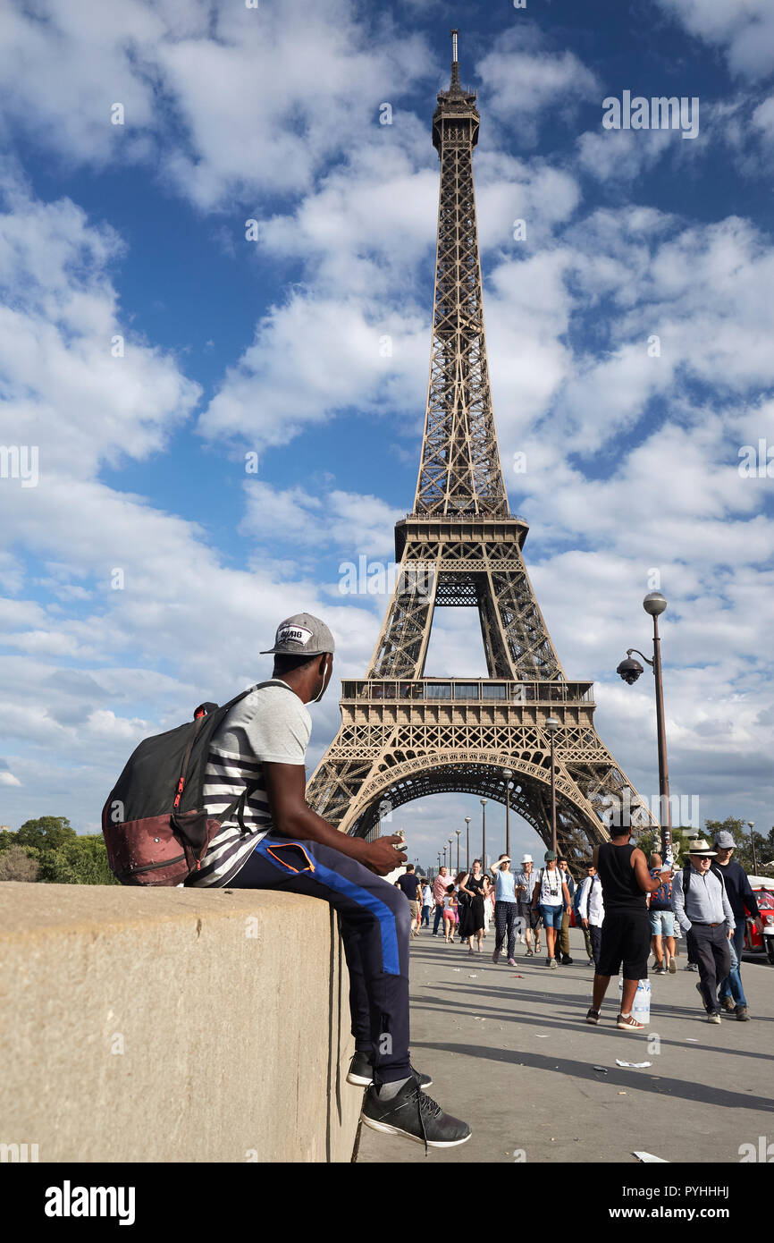 Parigi, Ile-de-France, Francia - Passanti e un giovane africano sul Pont d'Iéna bridge e sullo sfondo la torre Eiffel - il principale punto di riferimento della capitale francese. Foto Stock