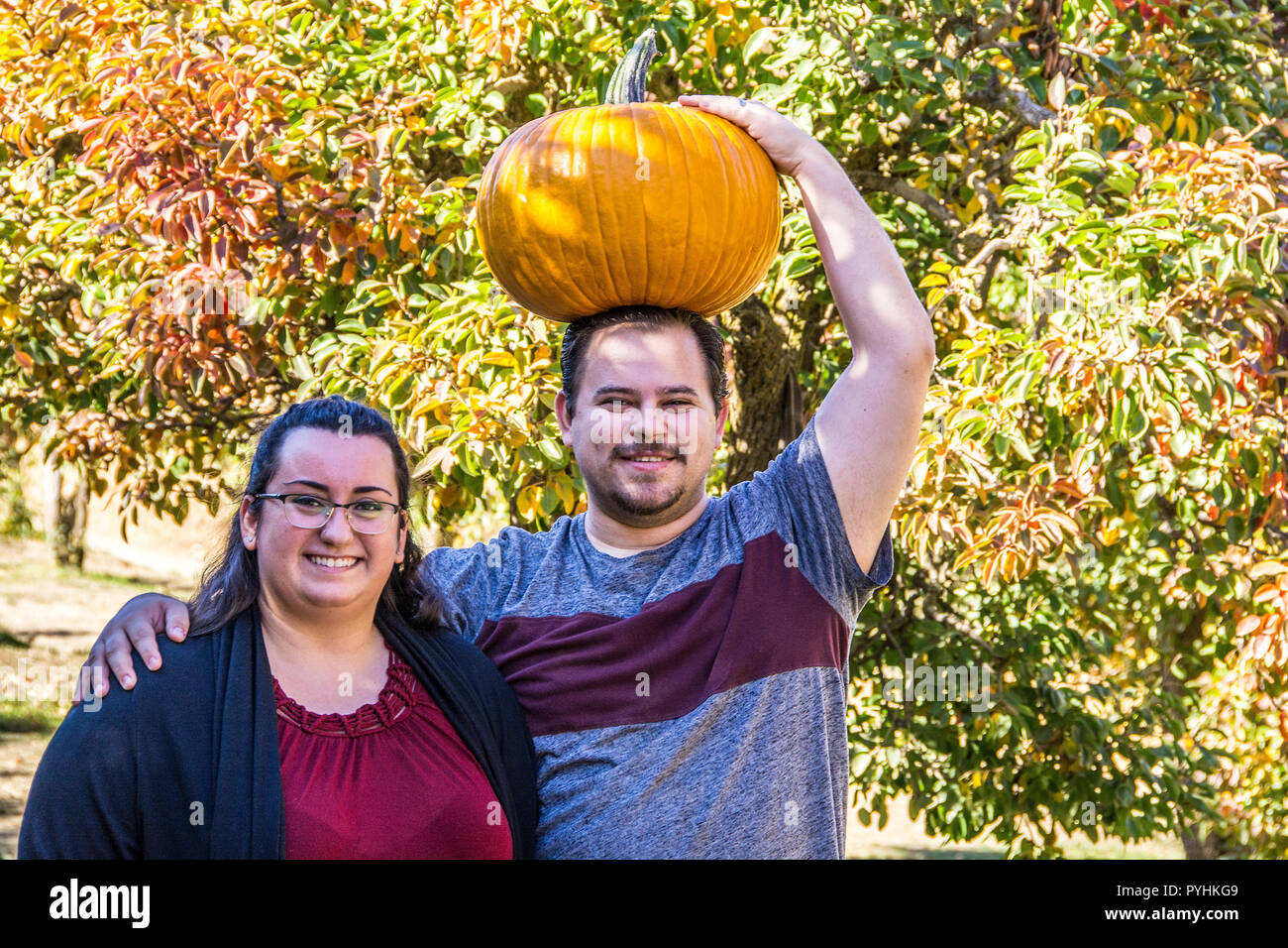 Uomo che cammina con la zucca sulla sua testa e la moglie dal suo lato; Oak Glen, California, U.S.A. Foto Stock