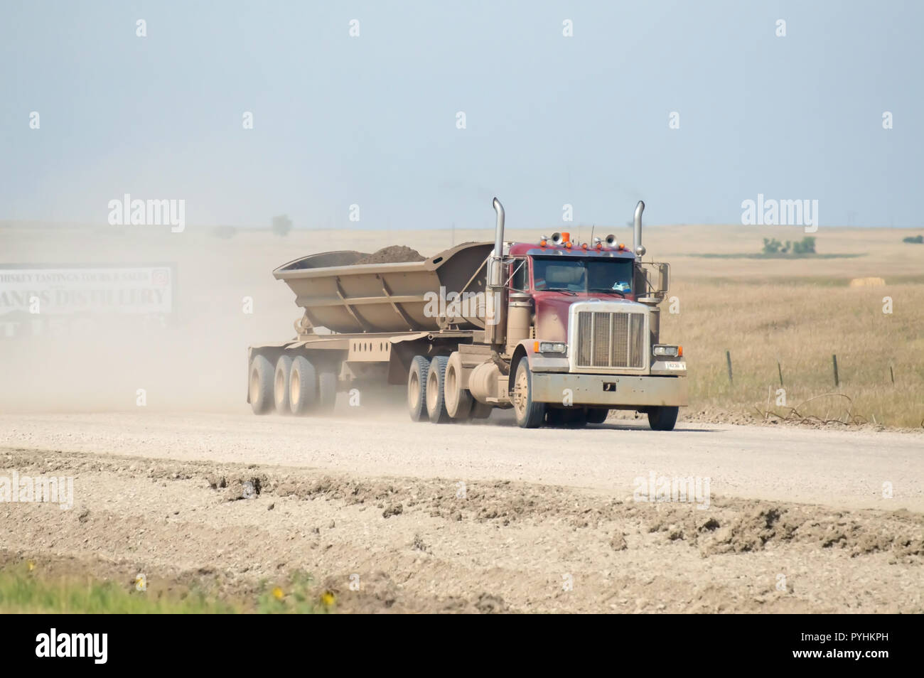 A scarico laterale semi carrello trasporta lo sporco verso il basso un deserto polveroso road. Foto Stock