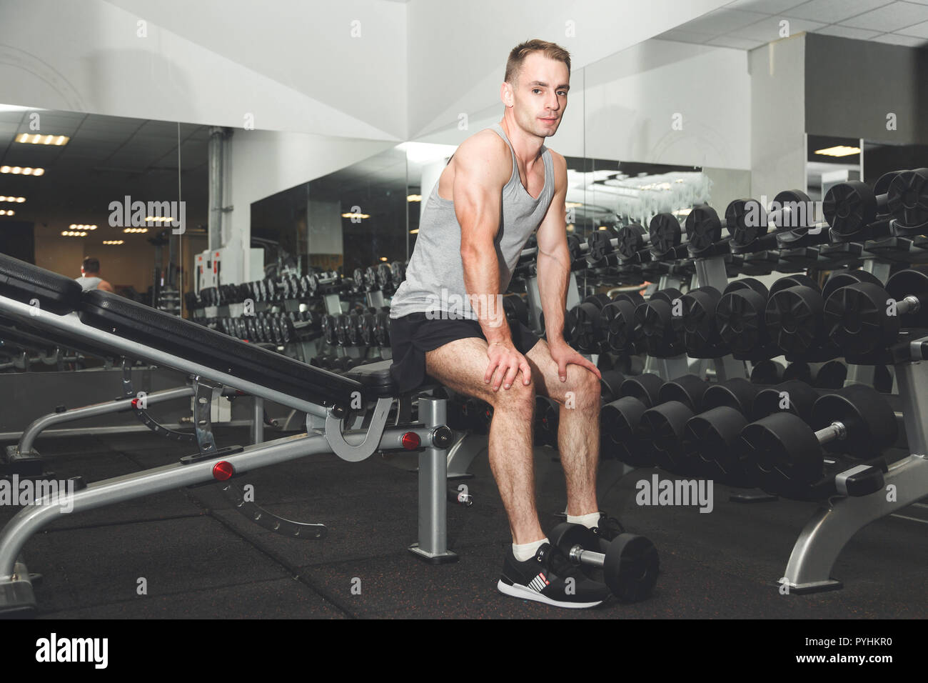 Bel giovane uomo latino indossando i guanti e seduta su una panchina in palestra Foto Stock