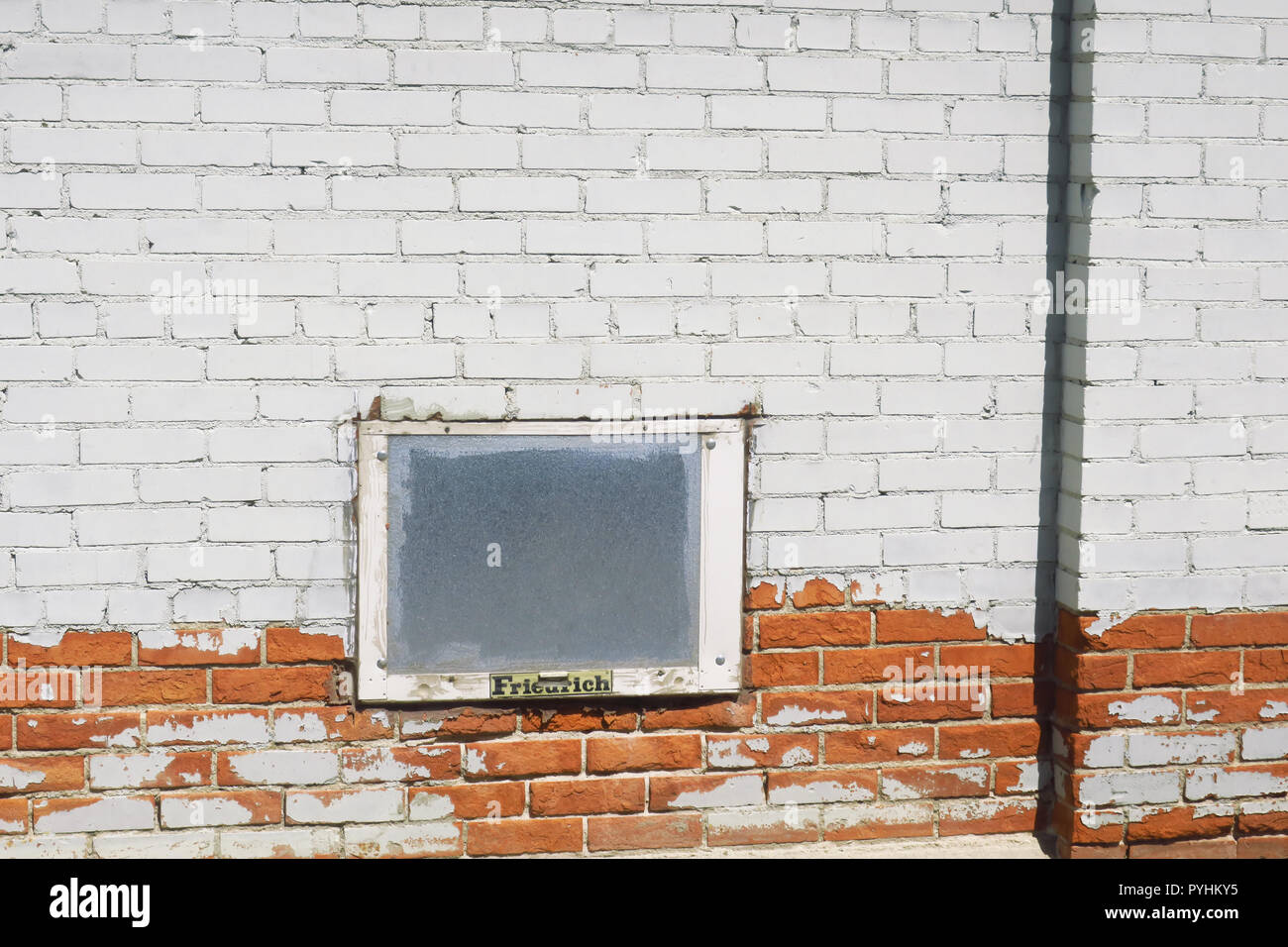 Una sbiadita il bianco e il rosso un muro di mattoni con un vetro smerigliato. Foto Stock