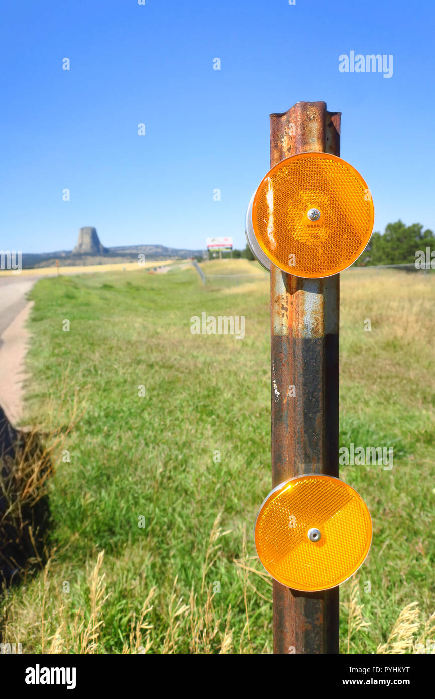 Guardando Devils Tower passato un arancio marcatore riflettente su un arrugginito post. Foto Stock