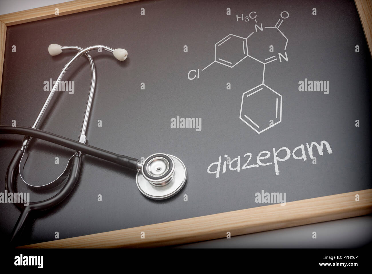 Formula chimica di diazepam scritto con gesso su una lavagna accanto a uno stetoscopio, immagine concettuale Foto Stock
