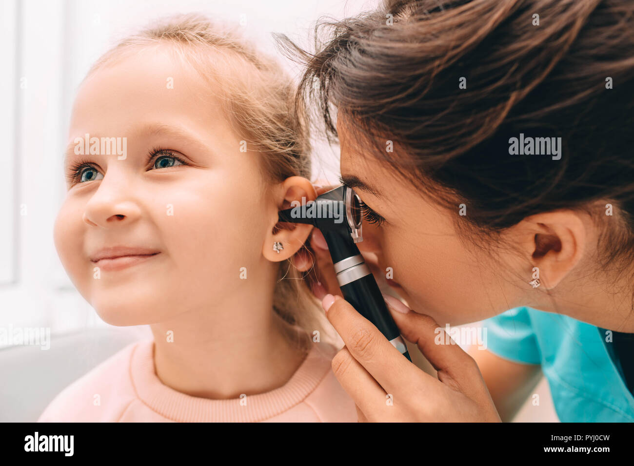 Sorridente bambina avente orecchio esame con otoscopio Foto Stock