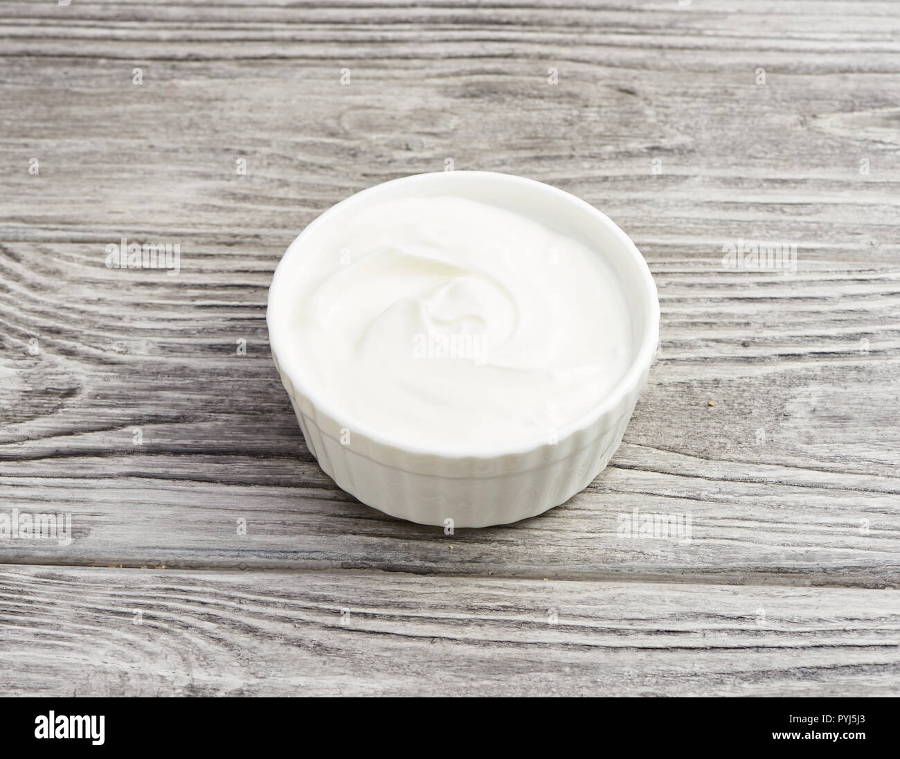 Ciotola di panna acida yogurt in grigio sullo sfondo di legno. Foto Stock