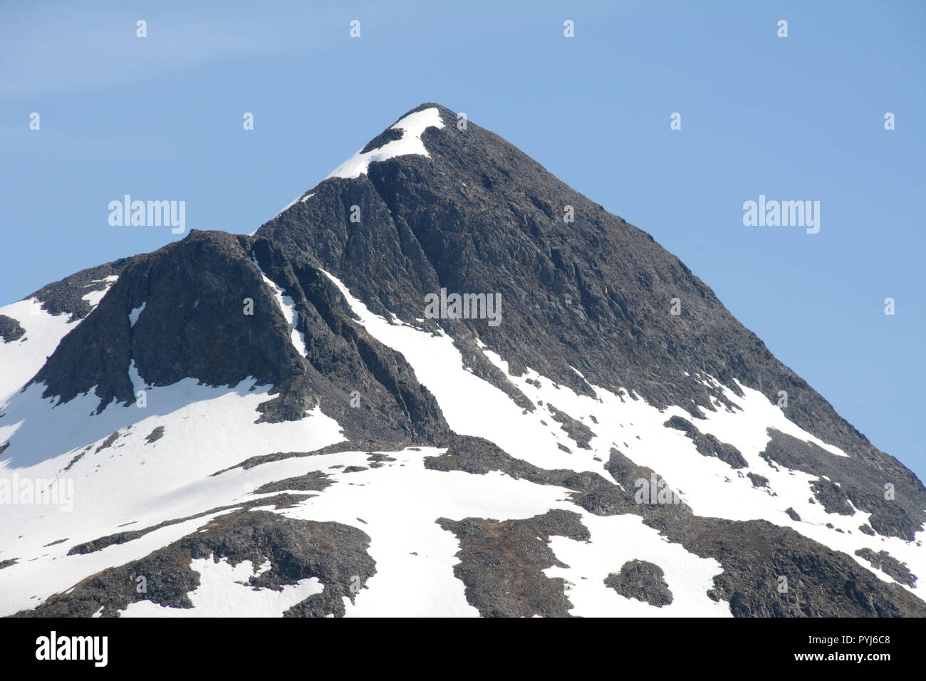 Un parzialmente coperte di neve montagna rocciosa picco sul isola di Unalaska, arcipelago di Isole Aleutine, Alaska, Stati Uniti. Foto Stock