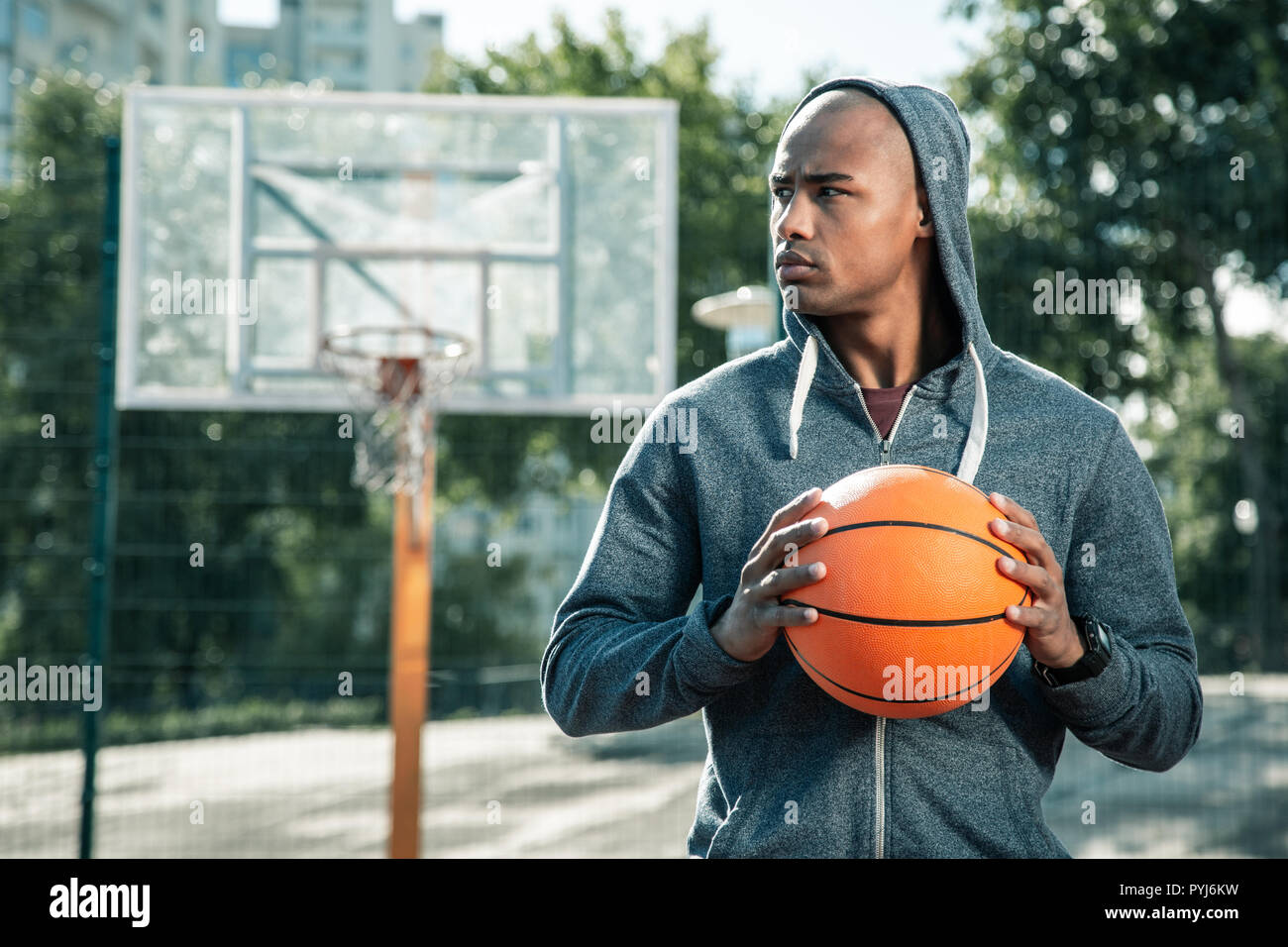 Giovane serio guardando il campo di pallacanestro Foto Stock