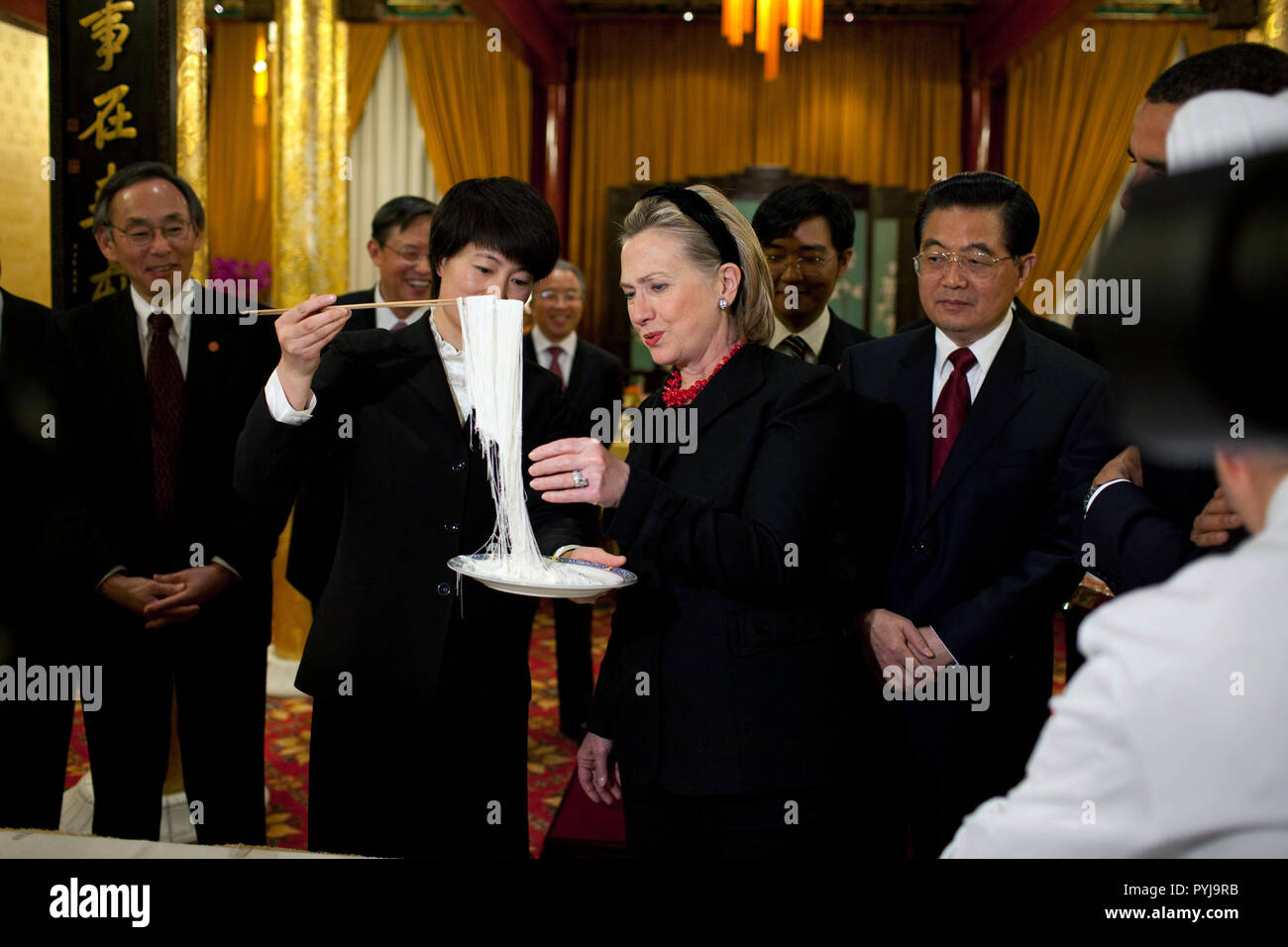 La delegazione americana, tra cui il segretario di Stato Hillary Rodham Clinton, orologi di una presentazione di noodle cinesi facendo mentre partecipavo a una cena ospitata dal presidente cinese Hu Jintao, a destra al Diaoyutai State Guest House di Pechino, Cina, nov. 16, 2009. Foto Stock