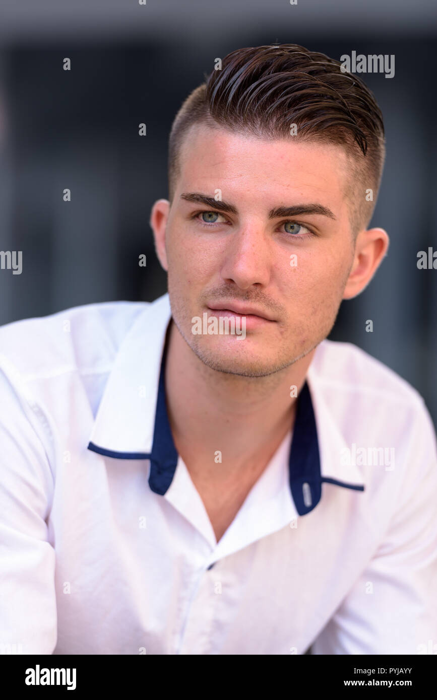 Volto del giovane uomo bello pensare al di fuori casa moderna Foto Stock