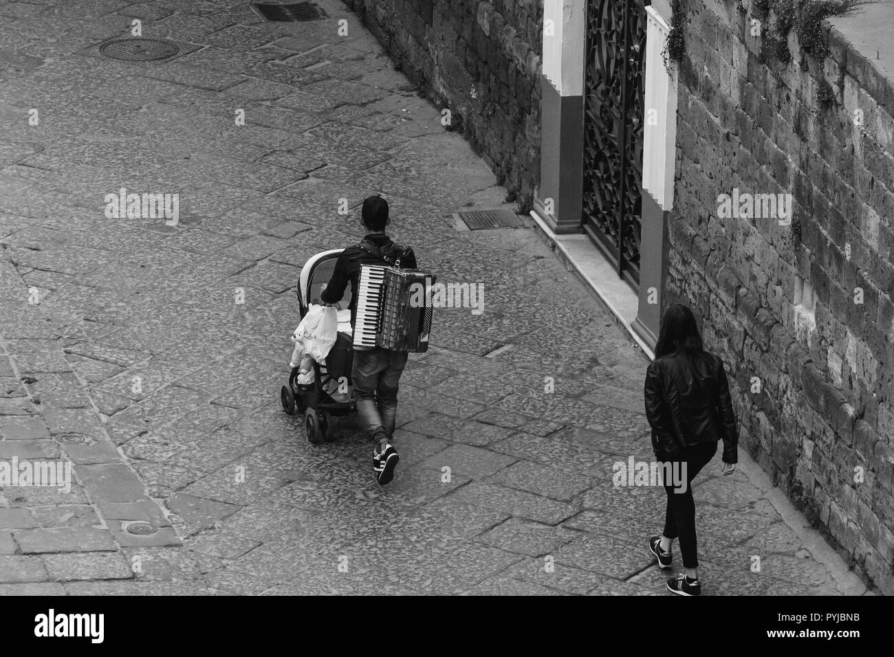 In bianco e nero giovane camminare per strada con il bambino e la fisarmonica Foto Stock