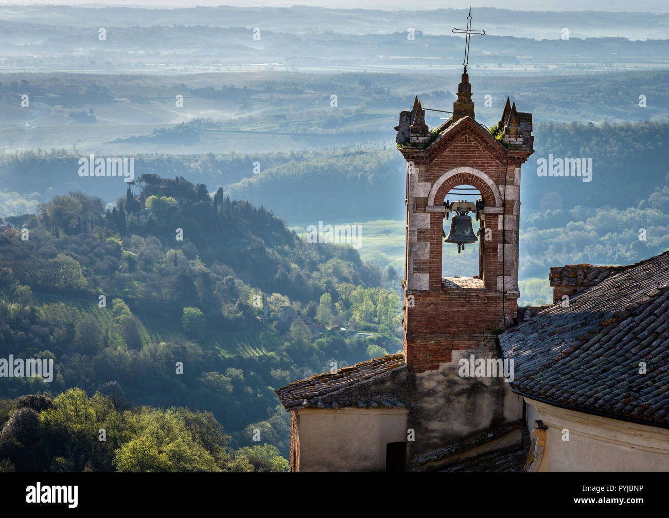 In churchsteeple Montepulcian Italia sunrise nebbia in colline Foto Stock