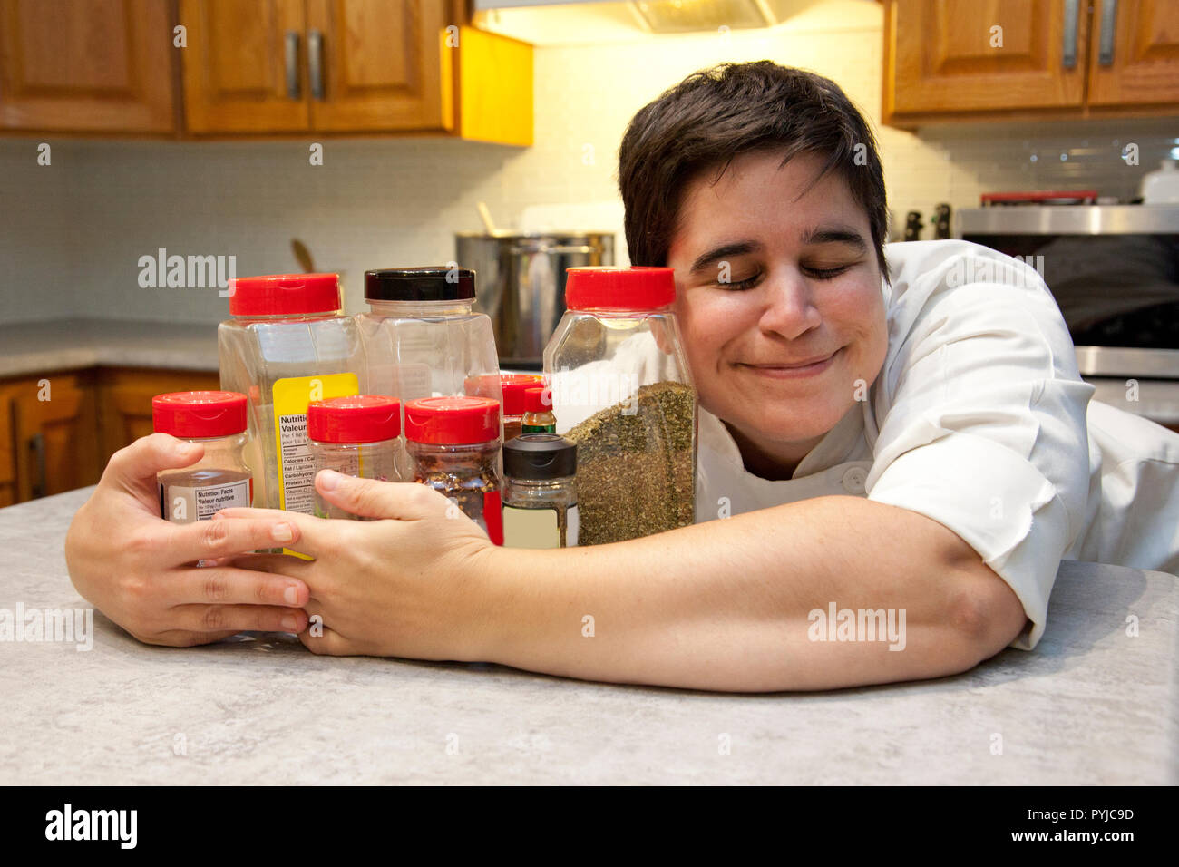 Un felice chef mantiene la sua collezione di spezie e condimenti vicino con una felice espressione Foto Stock