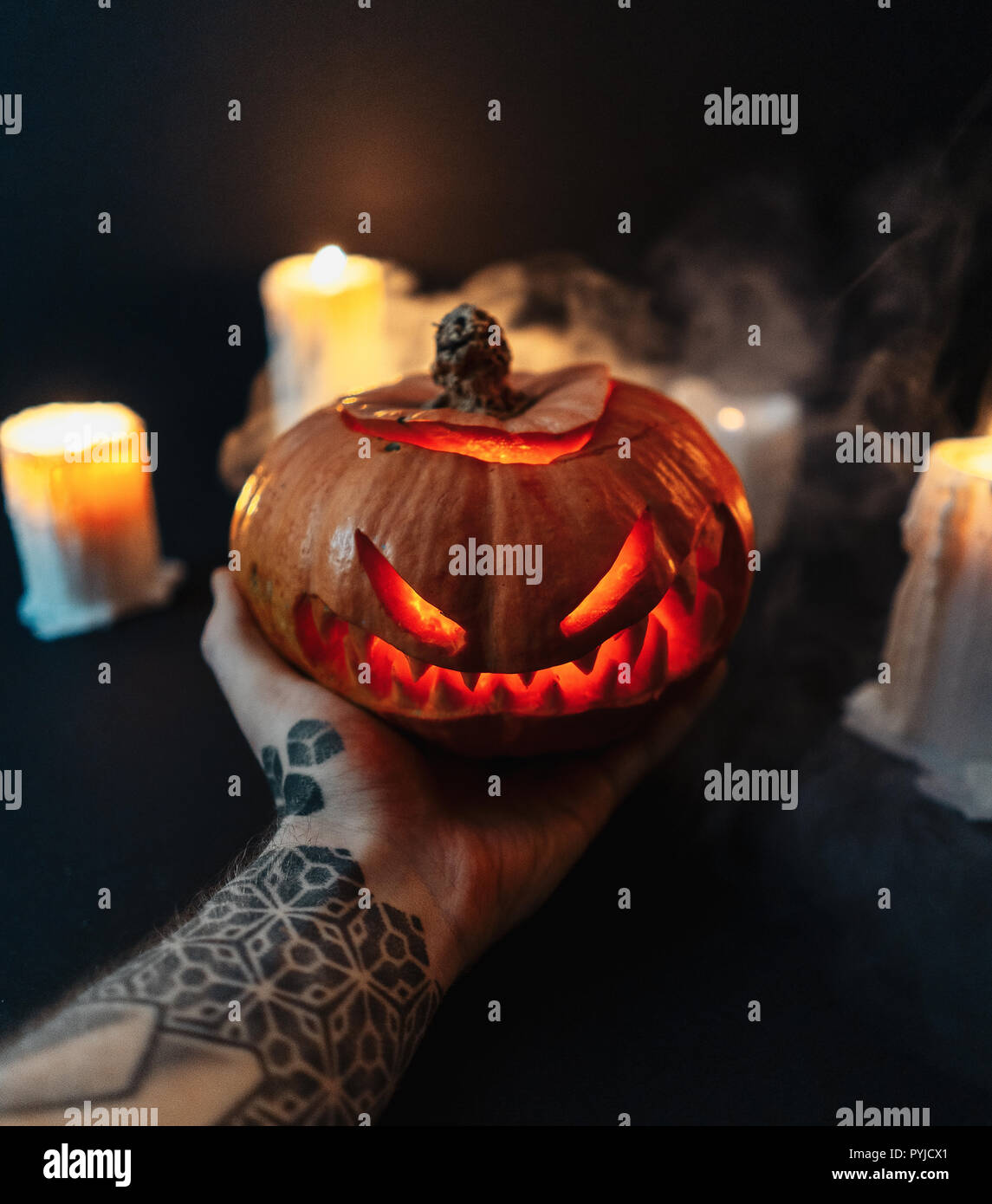 Man mano che tiene scolpita la zucca di Halloween su sfondo scuro. Foto Stock