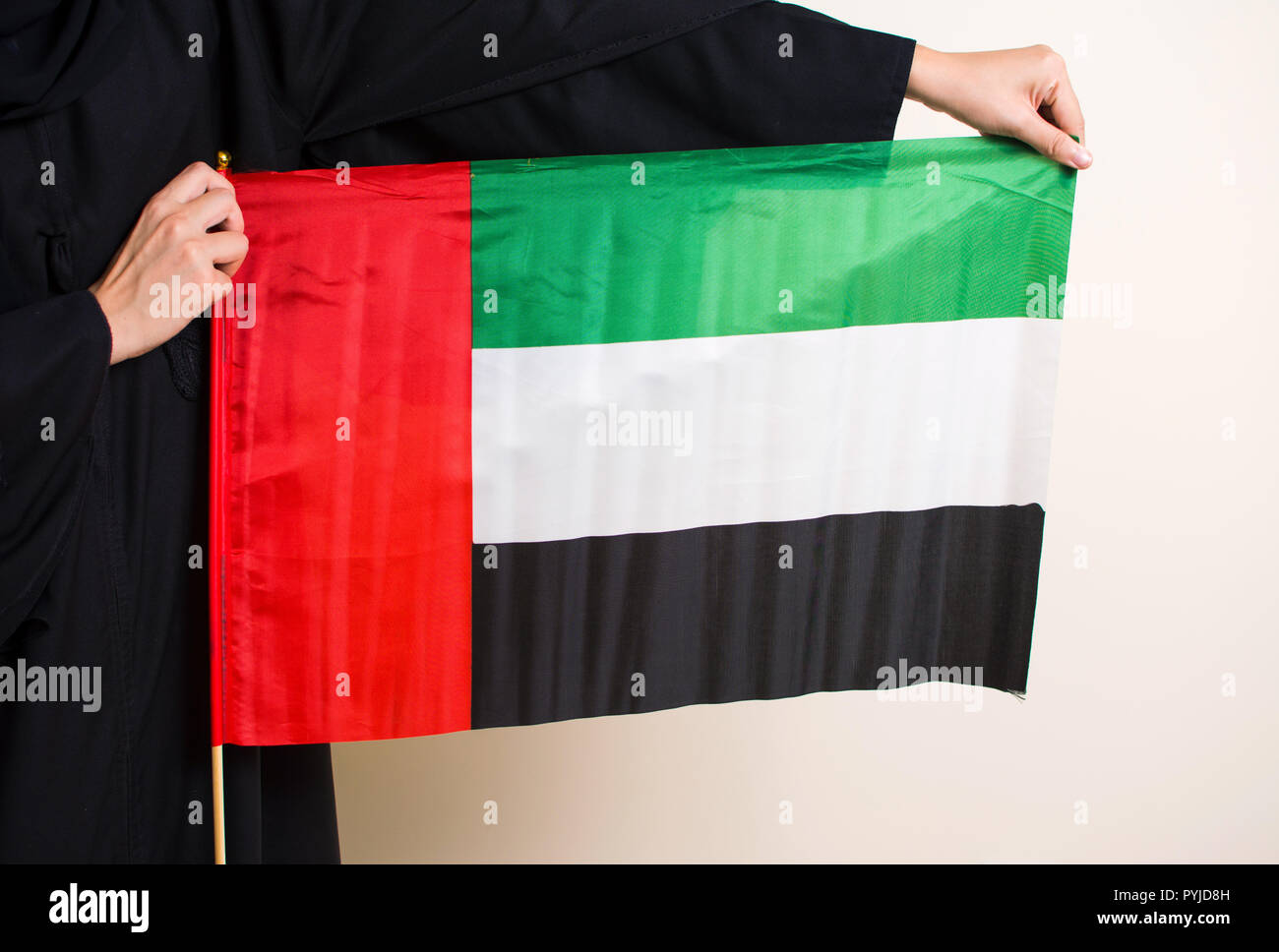 Donna in abaya holding Bandiera degli Emirati Arabi Uniti closeup Foto Stock