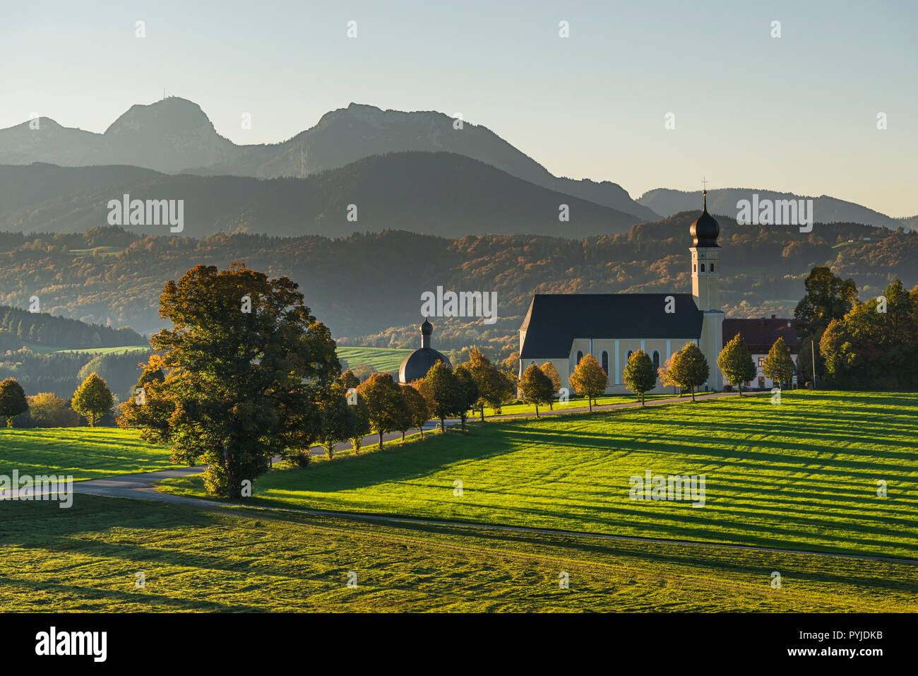 La barocca Chiesa di pellegrinaggio in Wilparting e colori d'autunno le foreste di fronte al Monte Wendelstein nel sole di mattina, Baviera, Germania Foto Stock