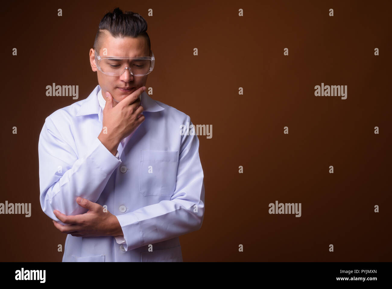 Giovane bello multi-etnico medico uomo contro lo sfondo marrone Foto Stock