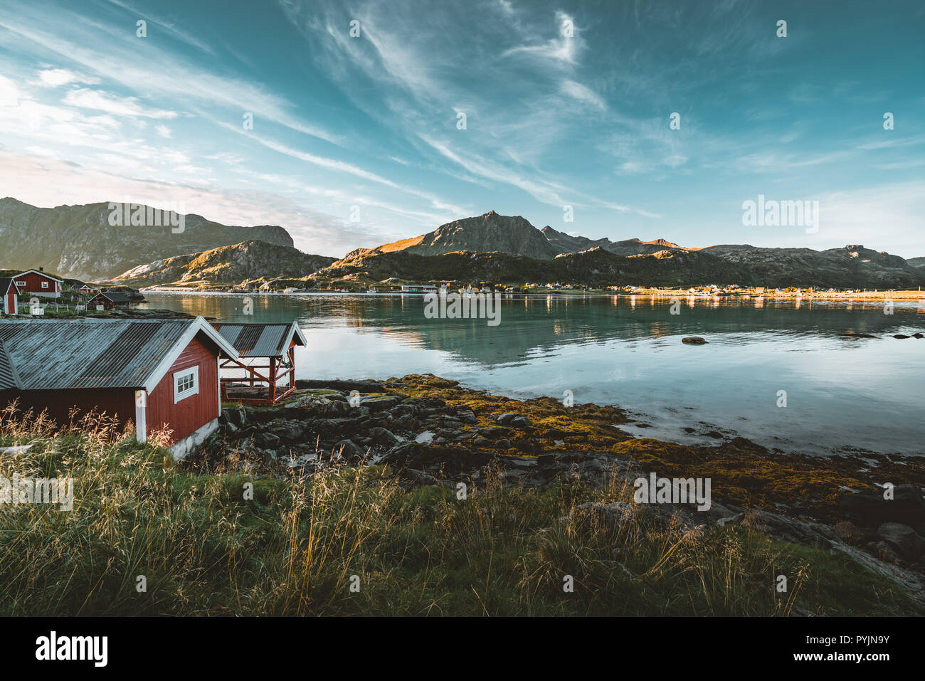 Tradizionale in rosso fishin casa in Bjoernsand vicino a Reine in Lofoten, Norvegia con red rorbu case. Pomeriggio al Tramonto con le nuvole su di una spiaggia di sabbia. Foto t Foto Stock