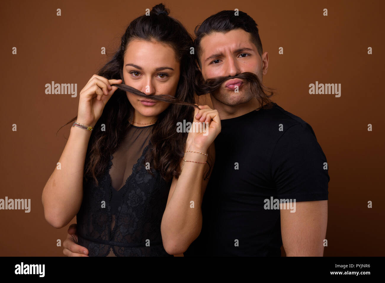 Coppia giovane insieme e in amore contro sfondo marrone Foto Stock