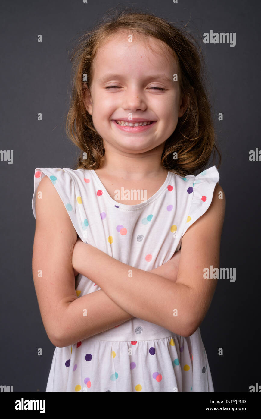 Carino ragazza giovane con capelli biondi contro uno sfondo grigio Foto Stock