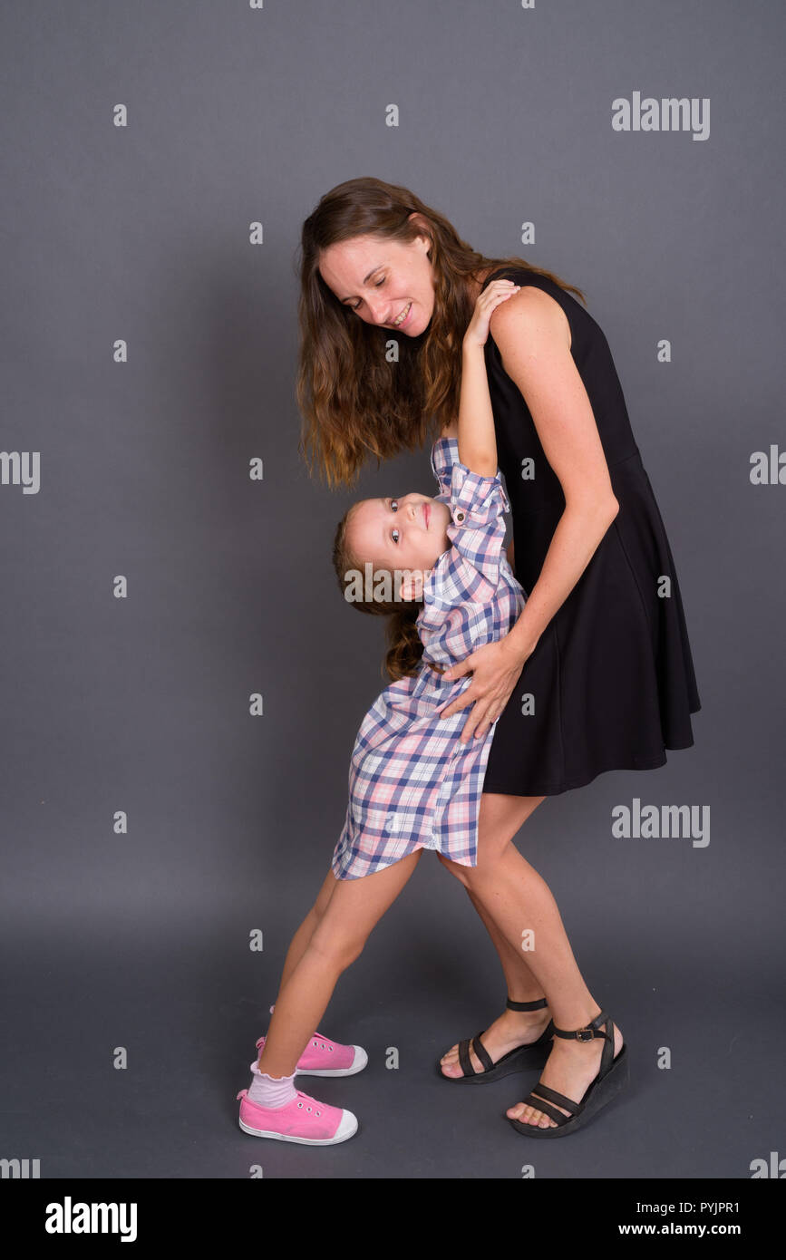 Madre e figlia insieme di incollaggio contro uno sfondo grigio Foto Stock