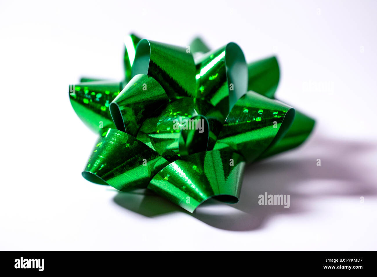 1 Singolo verde satinato vacanze di Natale la confezione regalo prua. La luce sullo sfondo bianco. Camera per copia. Foto Stock