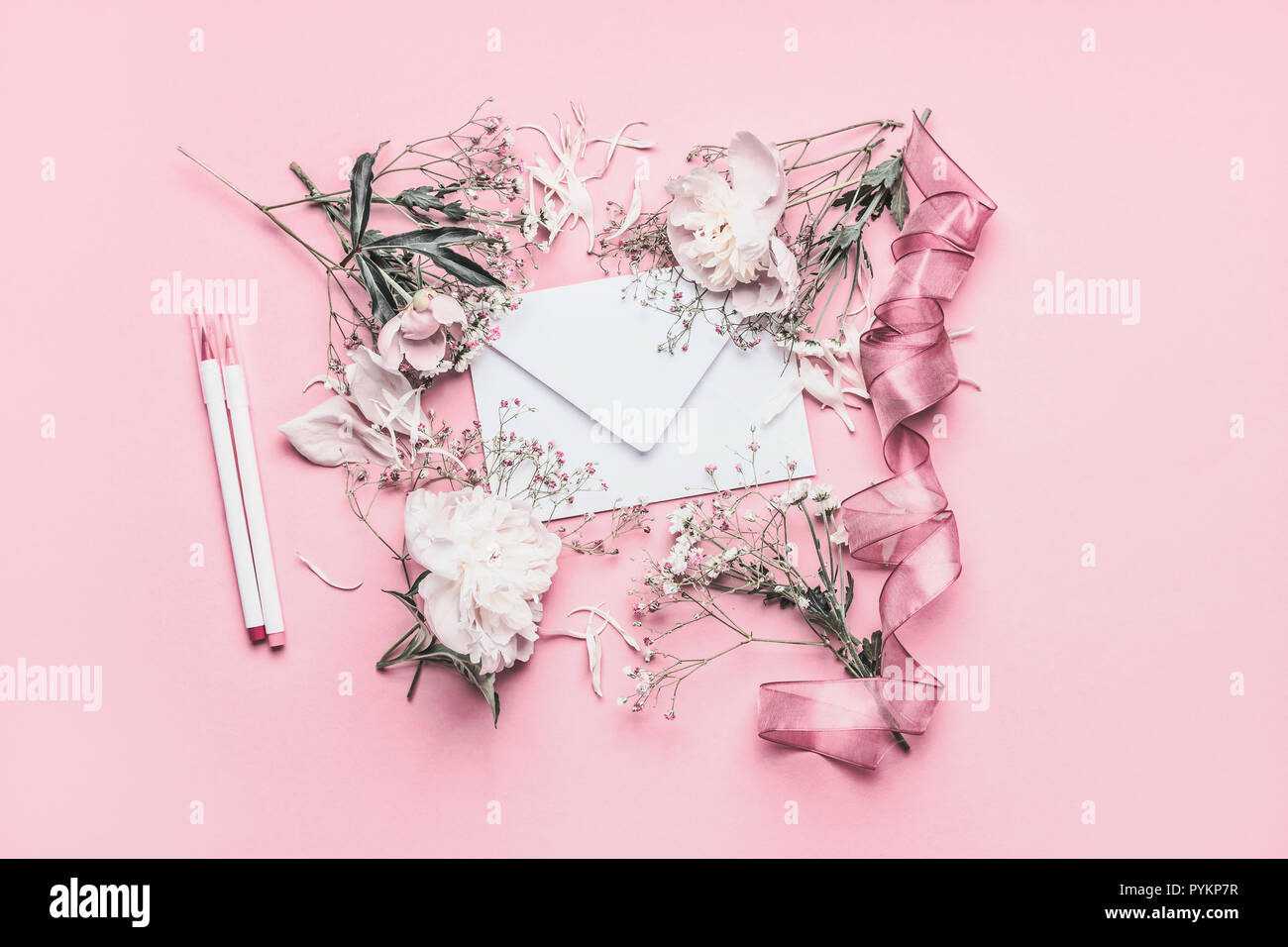 La composizione con il bianco le peonie, Busta, nastro e marcatori sul rosa pastello sfondo, vista dall'alto , copiare lo spazio per il tuo design Foto Stock