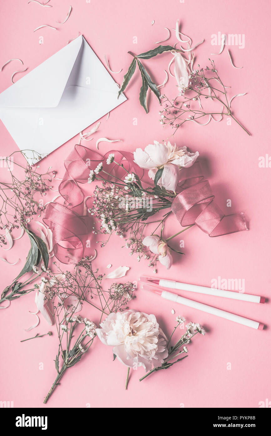 Appartamento stabilire la composizione con il bianco le peonie, Busta, nastro e marcatori sul rosa pastello sfondo, vista dall'alto , copiare lo spazio per il tuo design Foto Stock