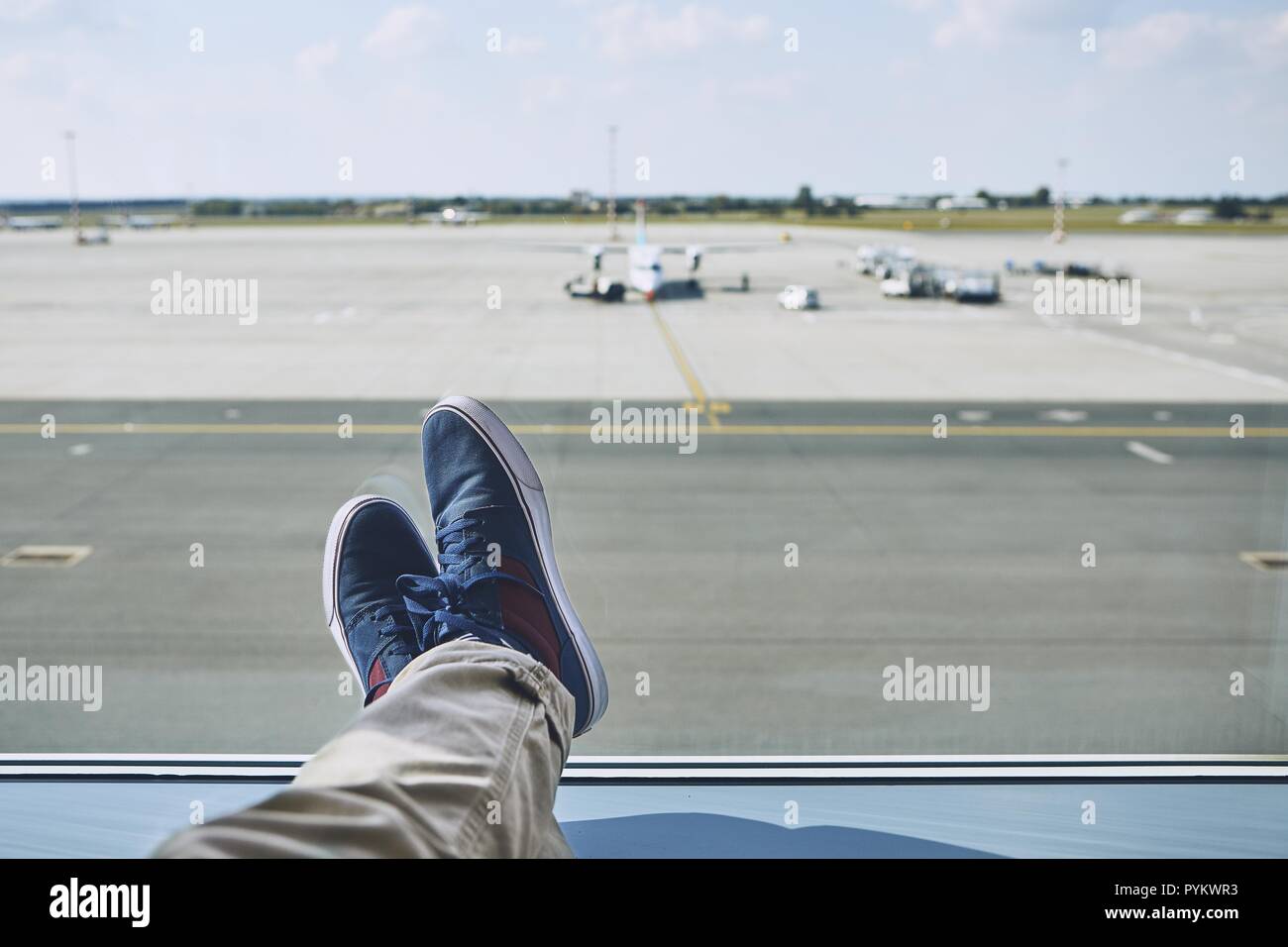 Uomo in attesa in aeroporto. Punto di vista personale del viaggiatore da finestra per vie di rullaggio e delle piste di atterraggio e di decollo. Foto Stock