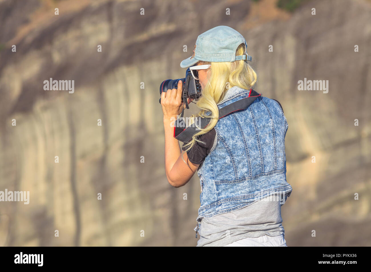 Traveler donna fotografo con fotocamera reflex presso i monasteri di Meteora in Grecia Centrale, Europa. Femmina caucasica fotografando un popolare punto di riferimento greco. Foto Stock
