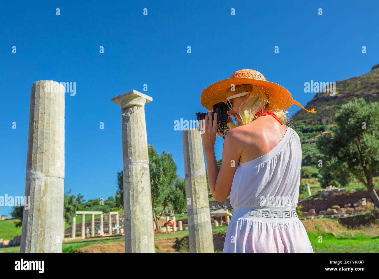 Donna Viaggi fotografo prende il colpo di Propylon dorico entrata , antica Messene, sito archeologico, Peloponneso, Grecia. Femmina caucasica fotografando un tempio greco.estate in Europa il concetto di viaggio Foto Stock