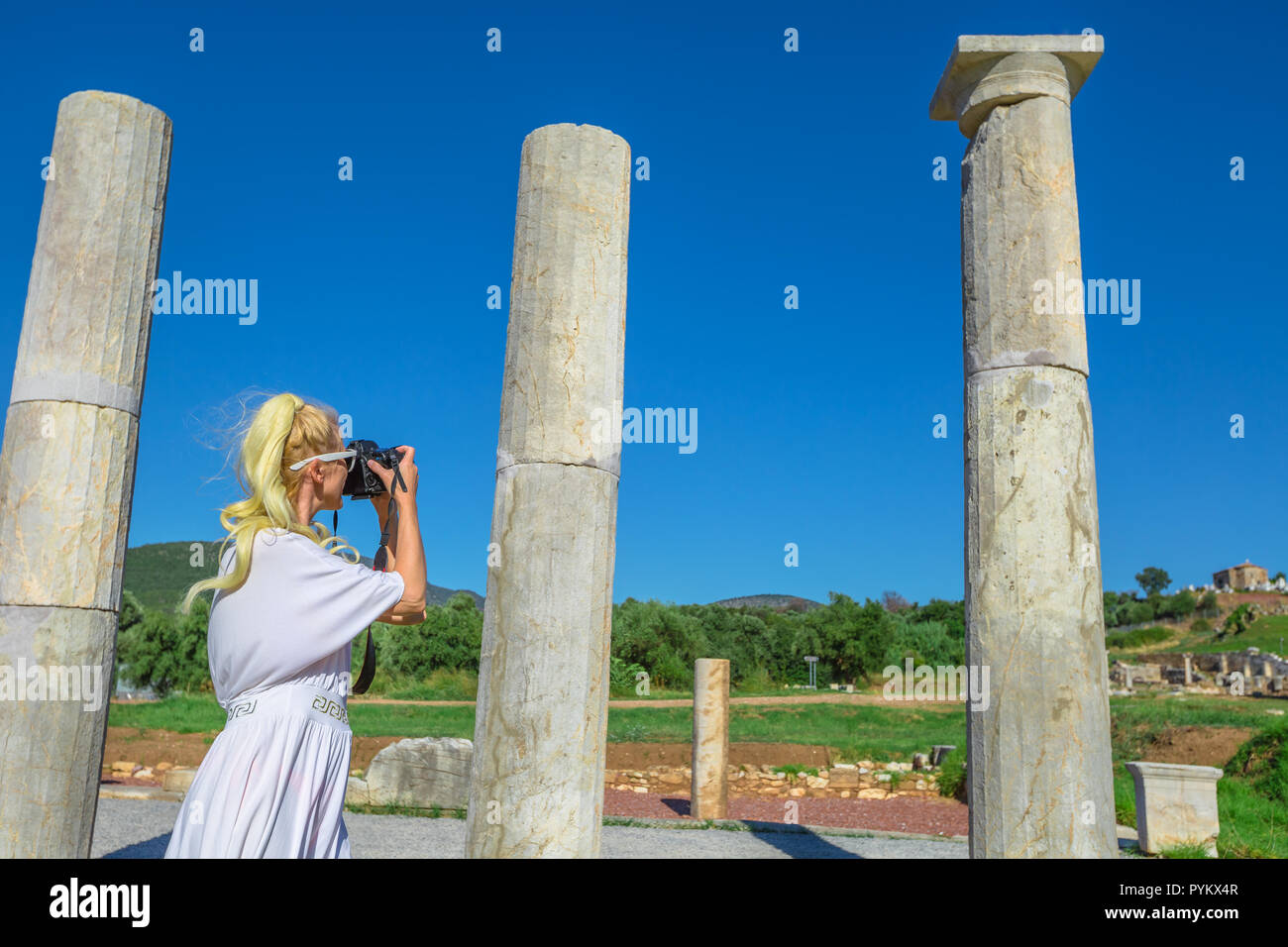 Femmina caucasica fotografando un tempio greco. La donna prende colpi di Propylon dorico entrata dell antica Messene, sito archeologico, Peloponneso, Grecia. estate concetto di viaggio. Foto Stock